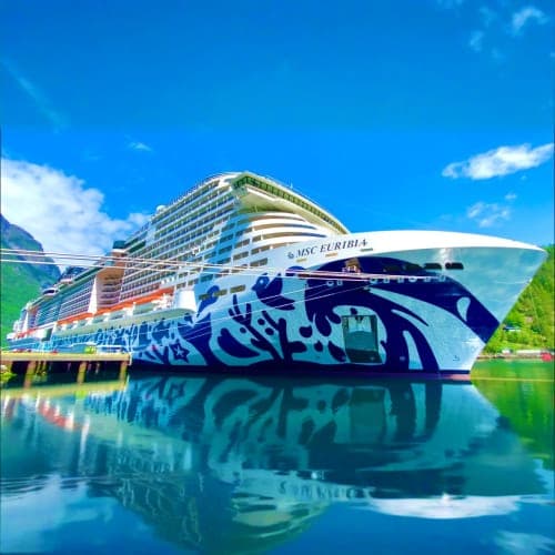 MSC Euribia cruise ship docked in calm blue water with mountains in background under clear sky